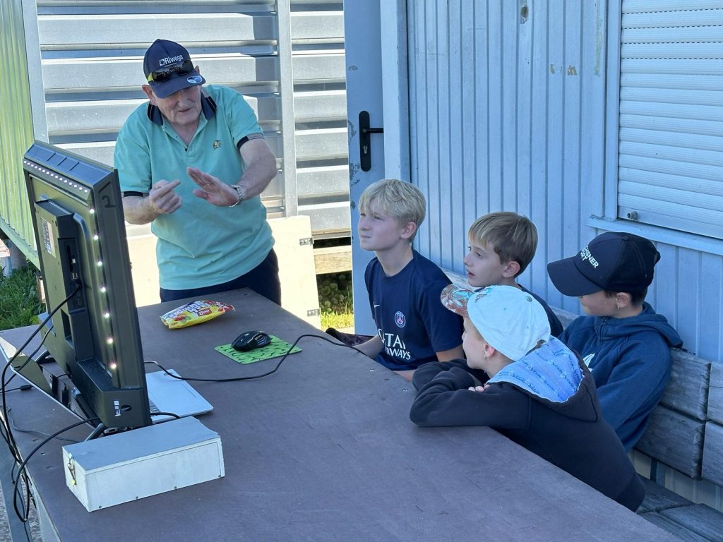 Ein Leiter erklärt den Kindern den Flugsimulator am Bildschirm